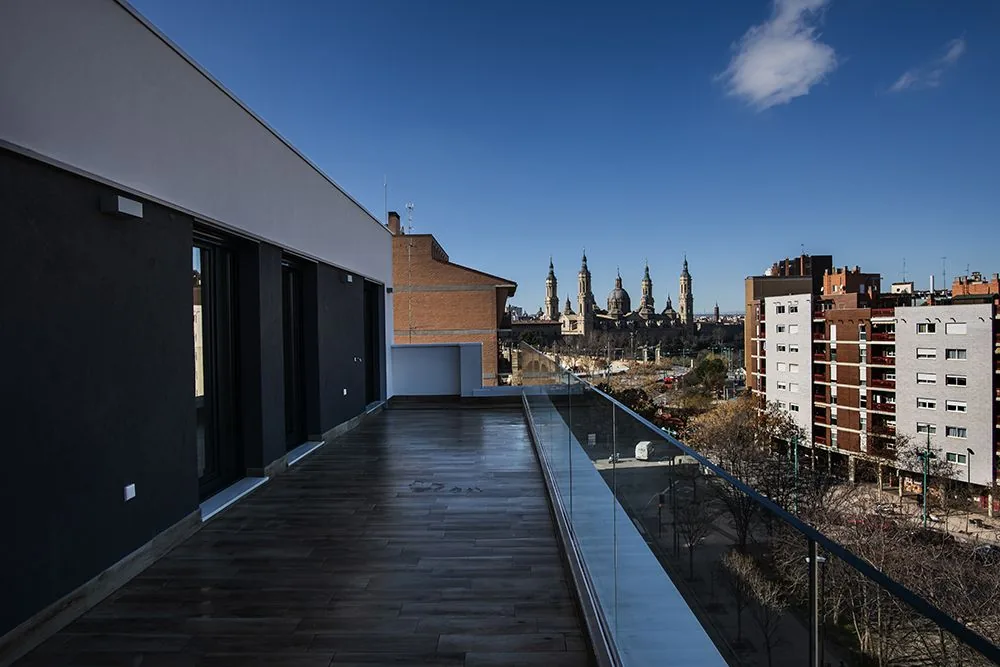 Terraza de ático con barandilla de vidrio y vistas a la ciudad